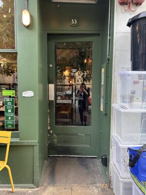 Green wood and glass door in green frame. Push from the left side to open.