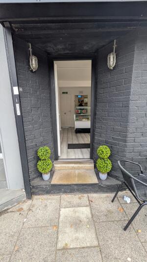 Glass door with white frame. Push handle on right to open.