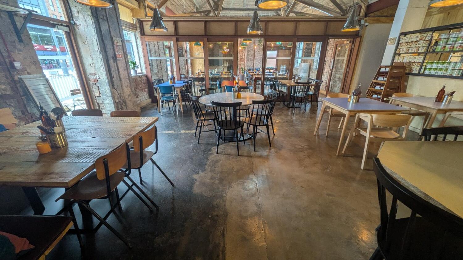 From after open kitchen facing straight. Tables and chairs to both sides, center and back.