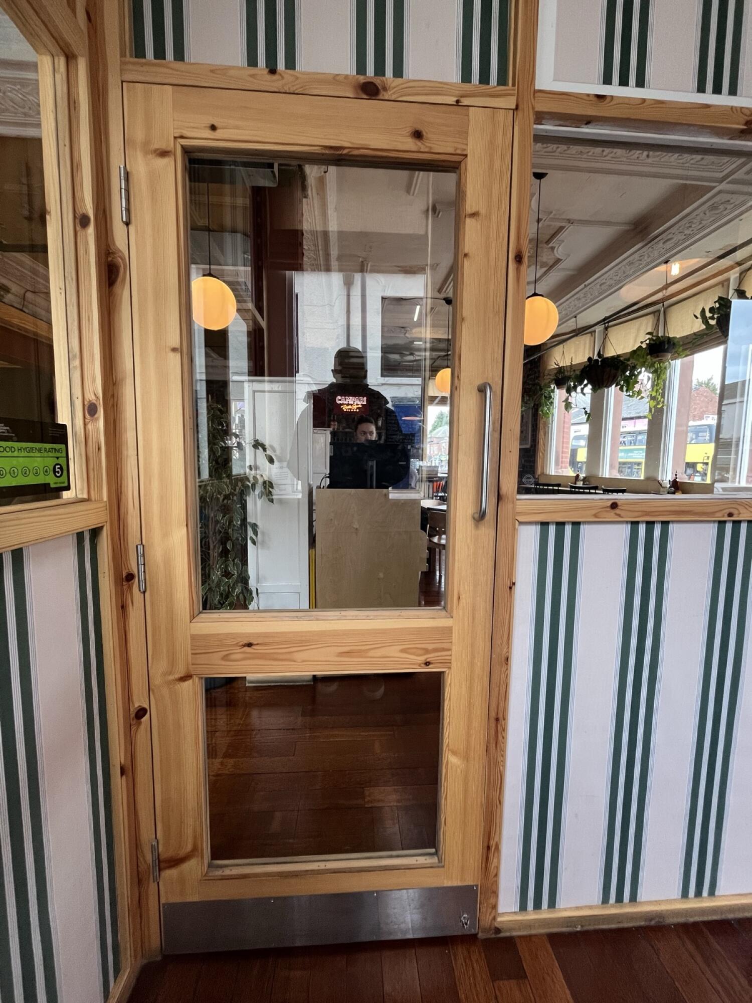From back wall facing right. Glass door with wooden frame. Handle on right. Pull to open.