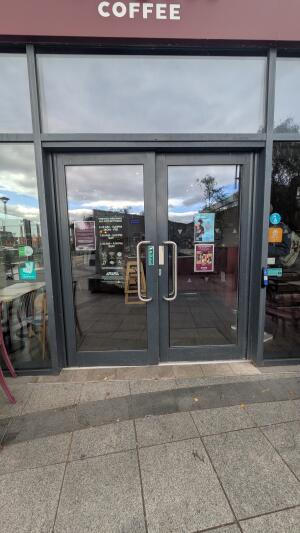 Glass doors with metal frame. Pull handles in center to open. Doorbell on right.