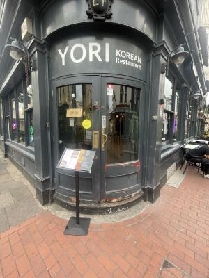 Glass doors with black frame ahead. Push gold metal handles from centre to open. Menu board on left.