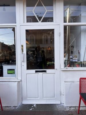 Glass door with white wooden frames ahead. Pull metal bar on the left to open.