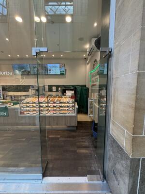 From mall corridor facing venue. Glass door ahead. Push silver handle on left to open door inwards.