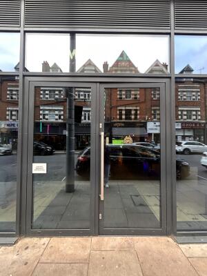 Glass doors with grey metal frames ahead. Push metal bar in center to open.