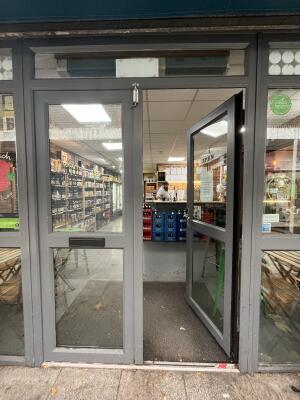 Glass double door with a grey frame. Metal handle on the right door. Push to open.