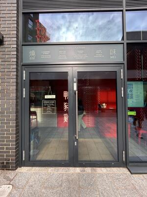 Glass doors with grey metal frames ahead. Pull metal bar in center to open.