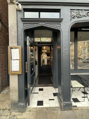 From sidewalk facing venue. Black framed glass door ahead. Pull door handle on right to open outward.