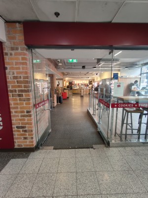 Facing entrance doors. Push silver metal handles in centre to open.