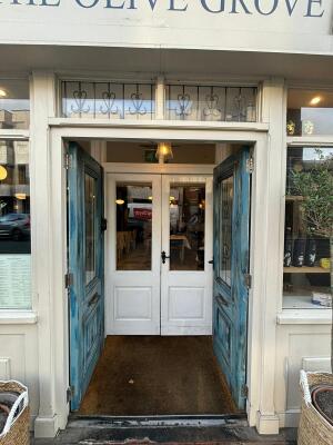 Blue doors with glass panels ahead. Push from centre to open. White framed glass doors behind. Push black handles in centre to open.