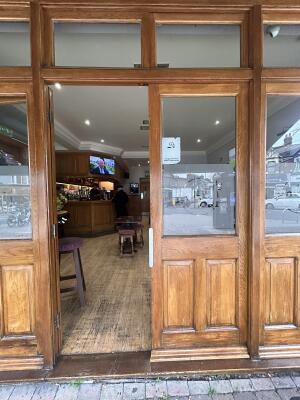 Glass doors with brown wooden frame ahead. Push from center to open.