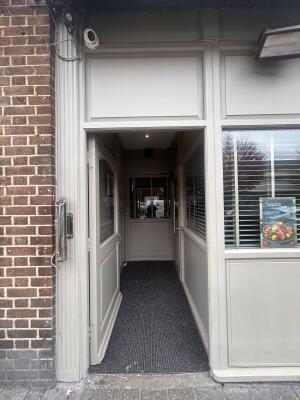 Glass door with grey wooden frames ahead. Push metal bar on right to open. Second door at back right.