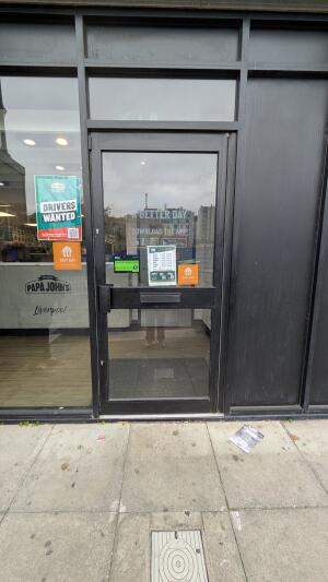 Glass door with black frame. Push handle on left to open.