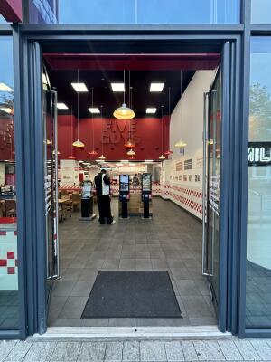 From sidewalk facing venue. Black framed glass doors ahead. Push silver handles in centre of door to open inward.