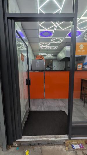 Glass door with black frame. Push handle on right to open