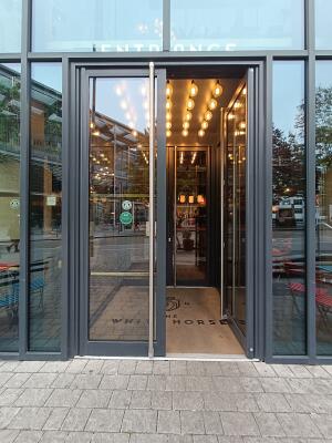 Glass doors with black, metal frames. Push from silver handles in middle to open.