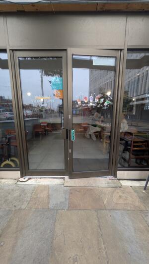 Glass doors with metal frame. Pull handle in center to open.