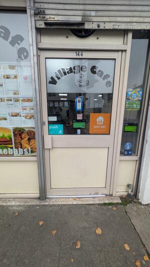 Glass door with white frame. Push handle on left to open.