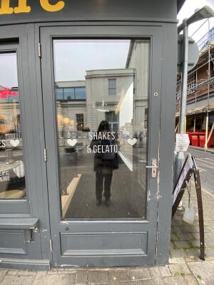 Grey framed glass door. Turn and pull the silver metal handle on right side of door to open.