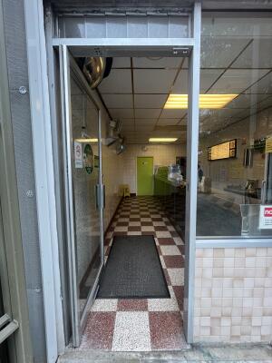 Glass door with grey frame and metal handle on right. Push to open.