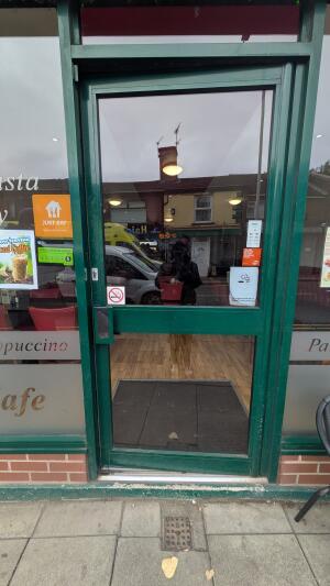 Glass door with green frame. Push handle on left to open.