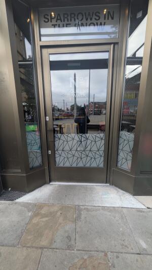 Glass door with black frame. Push handle on left to open