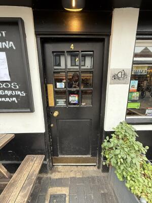 Black wooden door with glass panelling ahead. Push from handle on left to open.