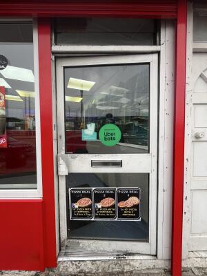 Glass door with a red frame and a metal handle on the left. Push to open.