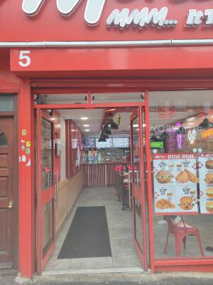 From sidewalk facing venue. Red framed double glass doors ahead. Push silver handle in centre to open.