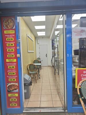 From sidewalk facing venue. Glass door with blue doorframe ahead. Push silver handle on left to open.