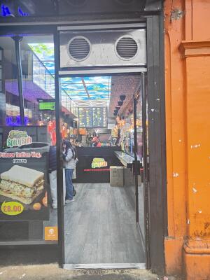 From sidewalk facing venue. Black framed single glass door ahead. Push black bar on left to open.