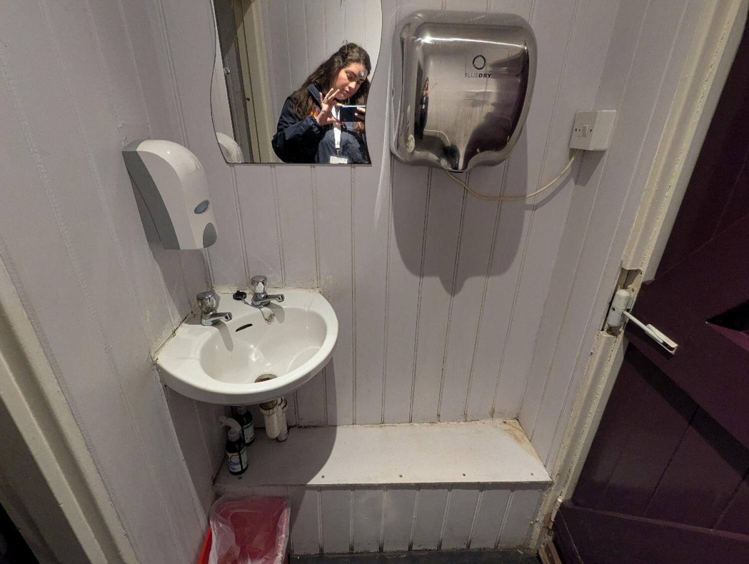 From front of door looking right. Sink on back wall.  Door to toilet on left.