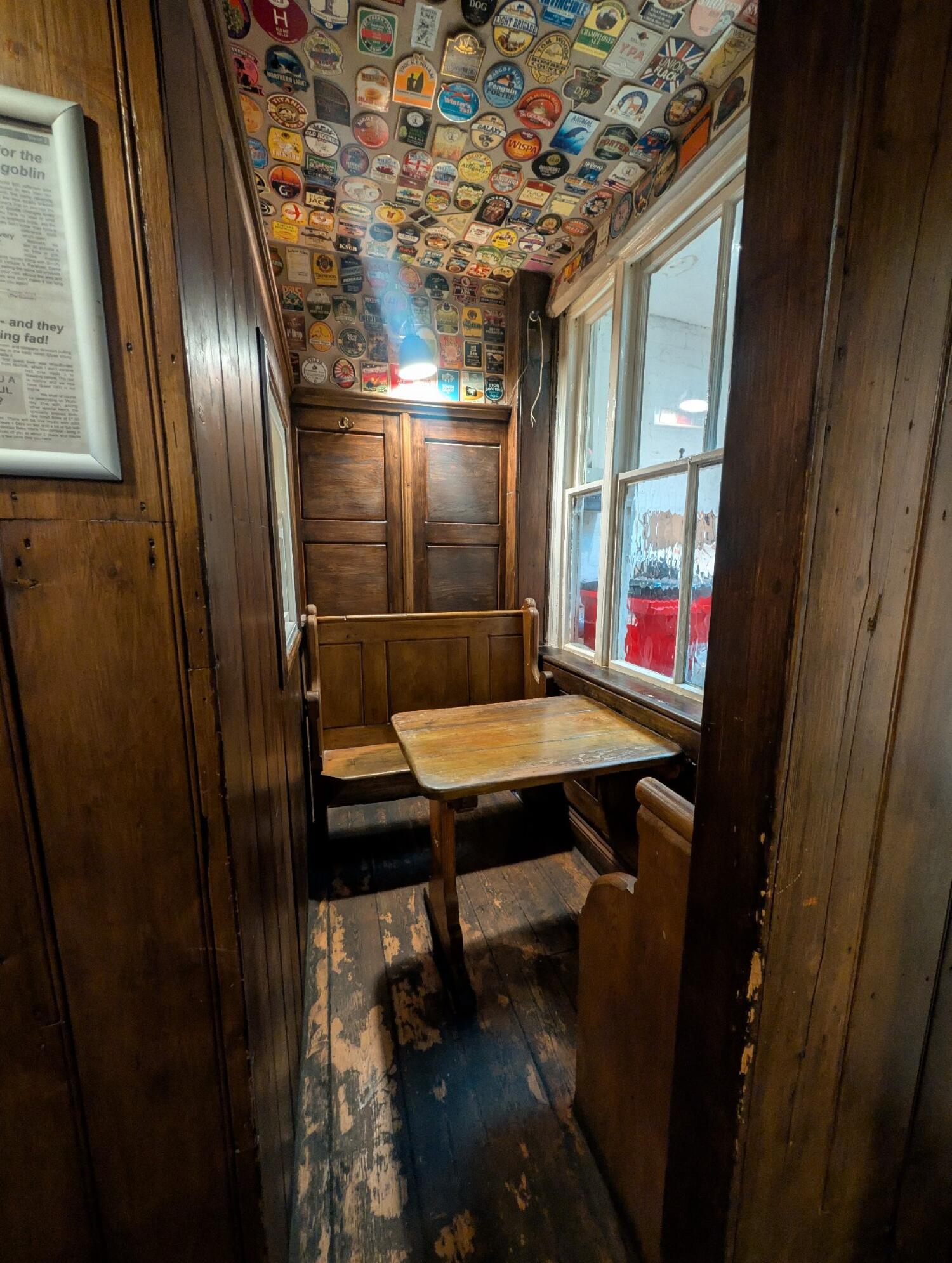 From path after chairs facing left. Wooden archway in front. Table and benches behind.