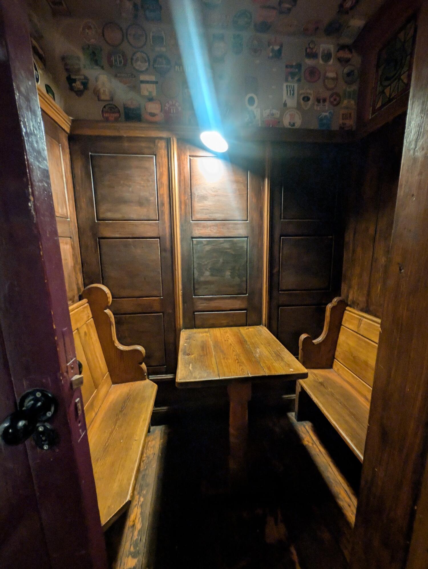 From path after chair facing right. Wooden archway in front. Table and benches behind.