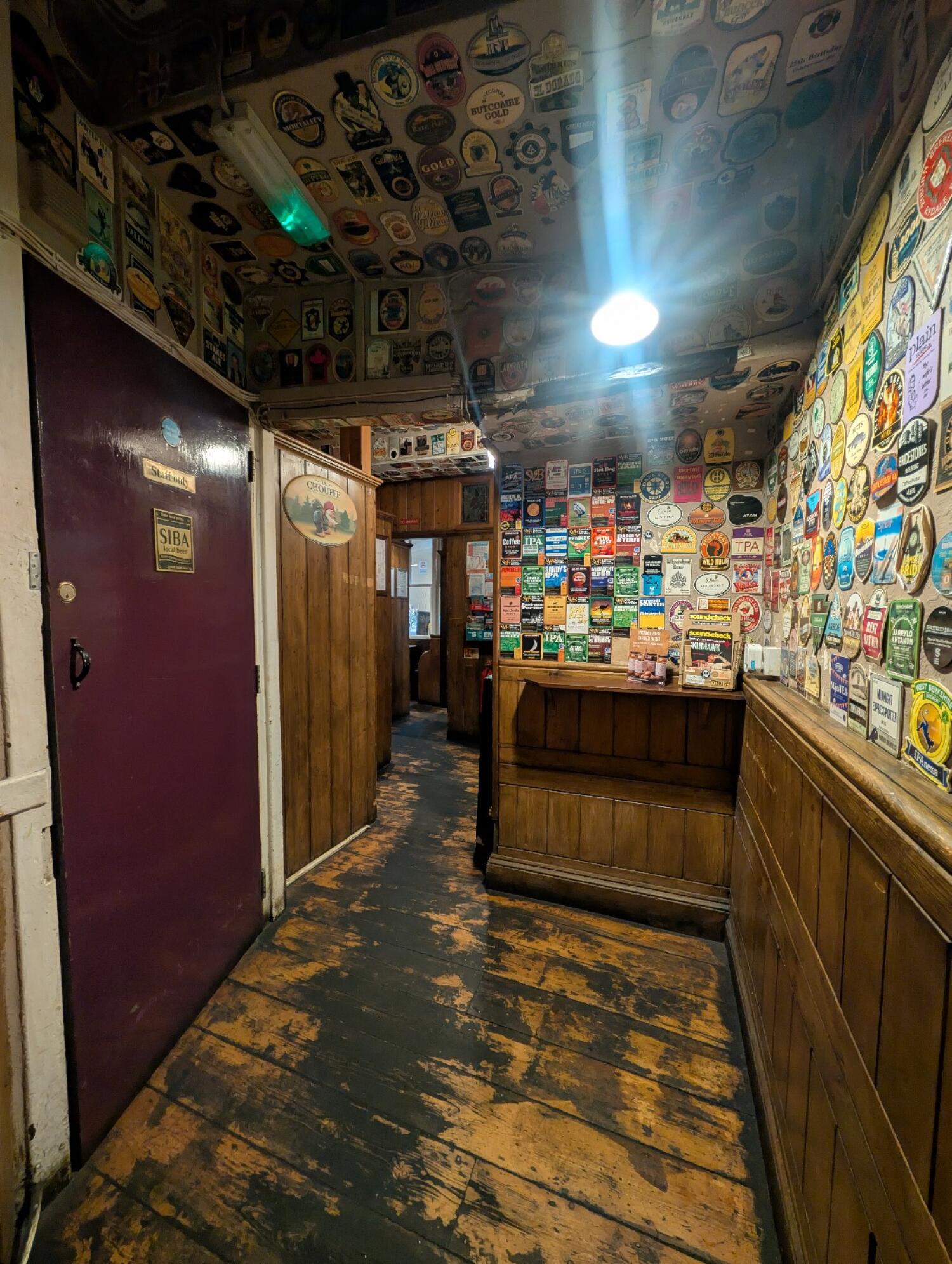 From archway facing straight. Staff door on left wall. Archway to more seating on back left. Standing area along right.