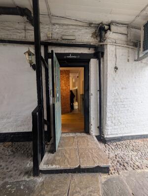 Black wooden door with glass panels. Metal handle on right. Pull to open.