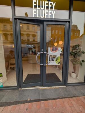 Black frame glass doors. Curved metal handle in center. Push to open.