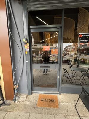 Glass door with grey frame ahead. Push via handle on right to open.