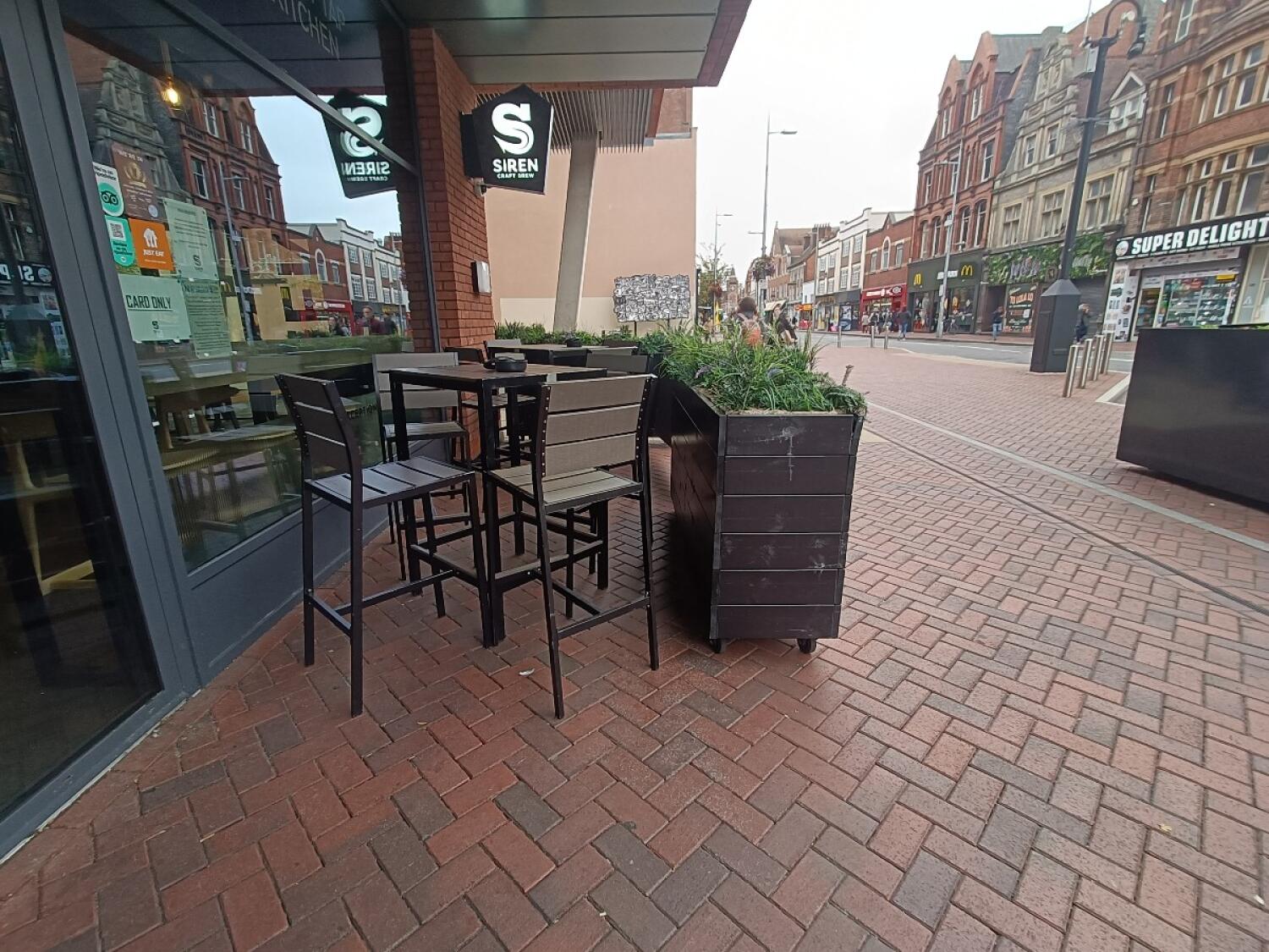 From entrance, facing right. Table and stools at back left. Planter at back right.