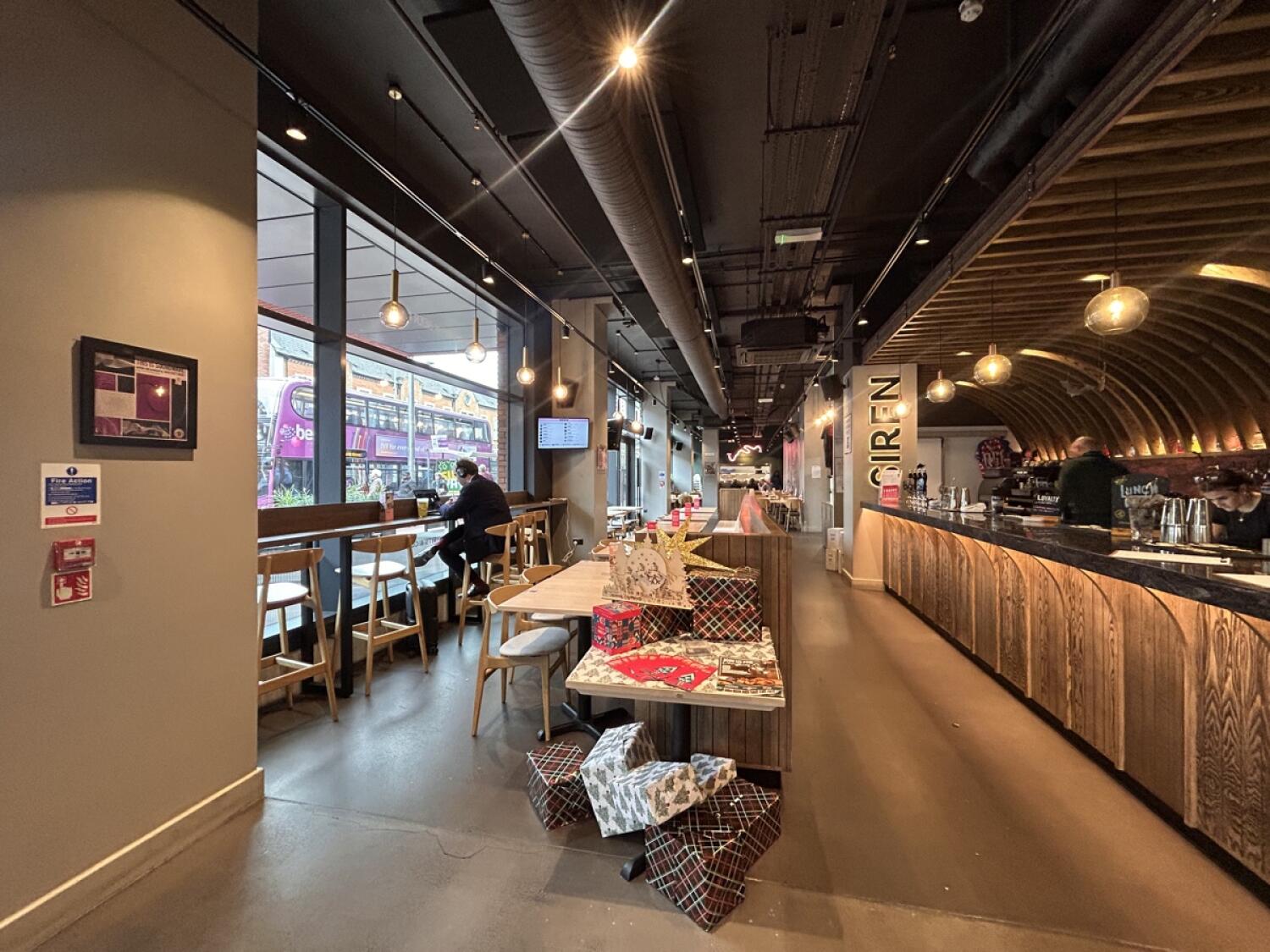 From entrance facing left. Stools and high-table on left wall. Half-booth in center. Bar counter on right.