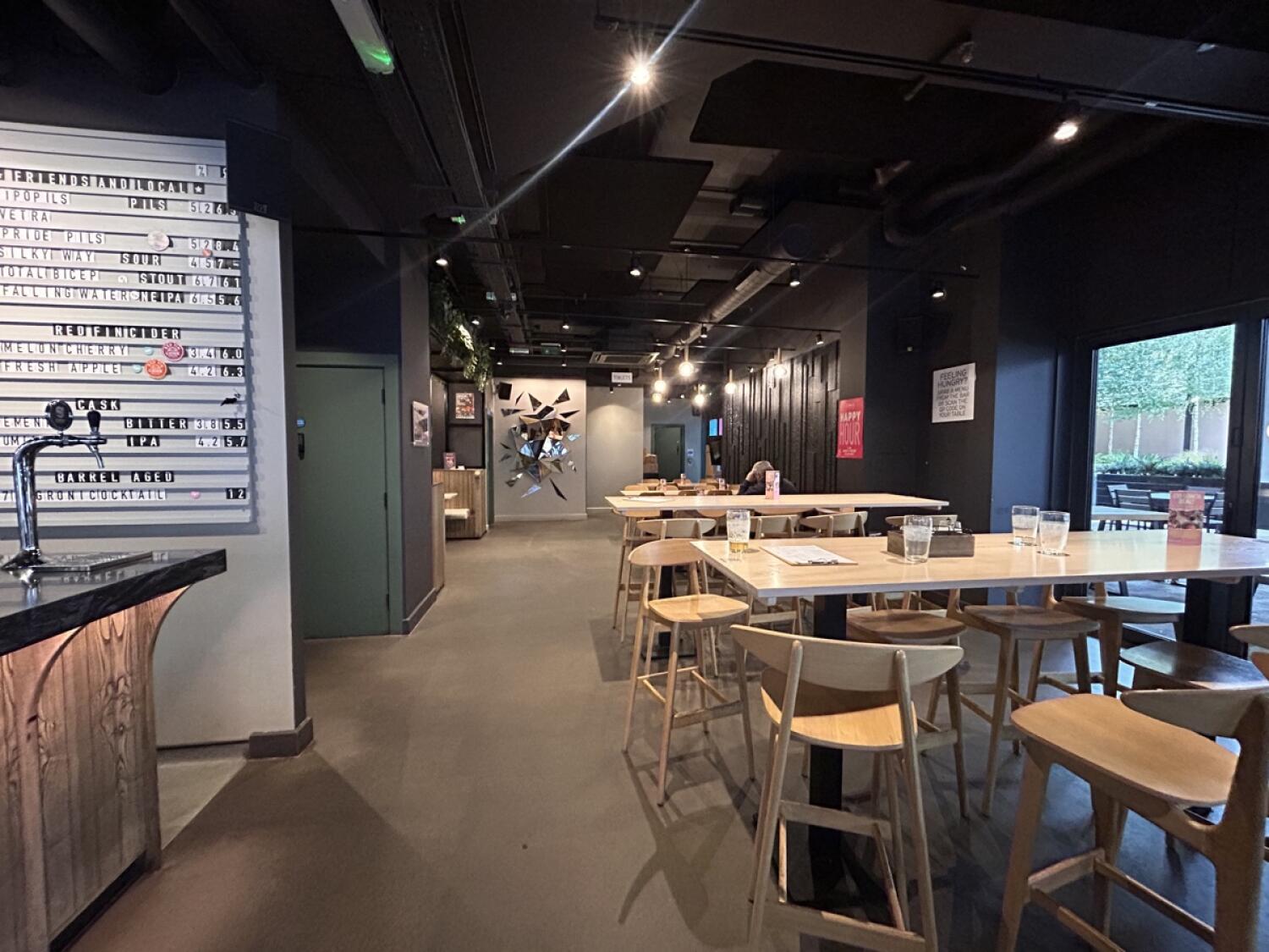 From right of counter facing straight. Wall partition on left. Accessible bathroom behind. Stools and high-tables on right.