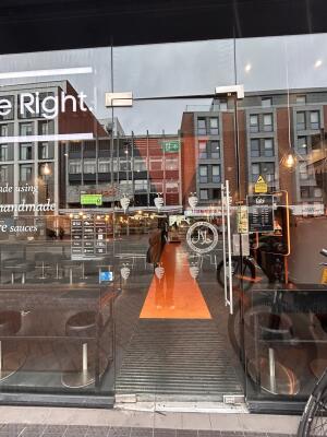 Glass door with glass frames ahead. Push metal bar from right to open.