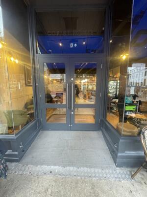 Glass doors with grey frame ahead. Pull silver metal handles from centre to open.