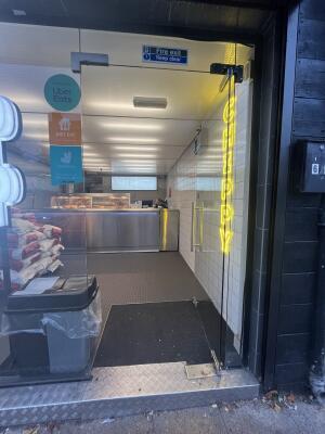 Glass door with metal handle on the right. Push to open.