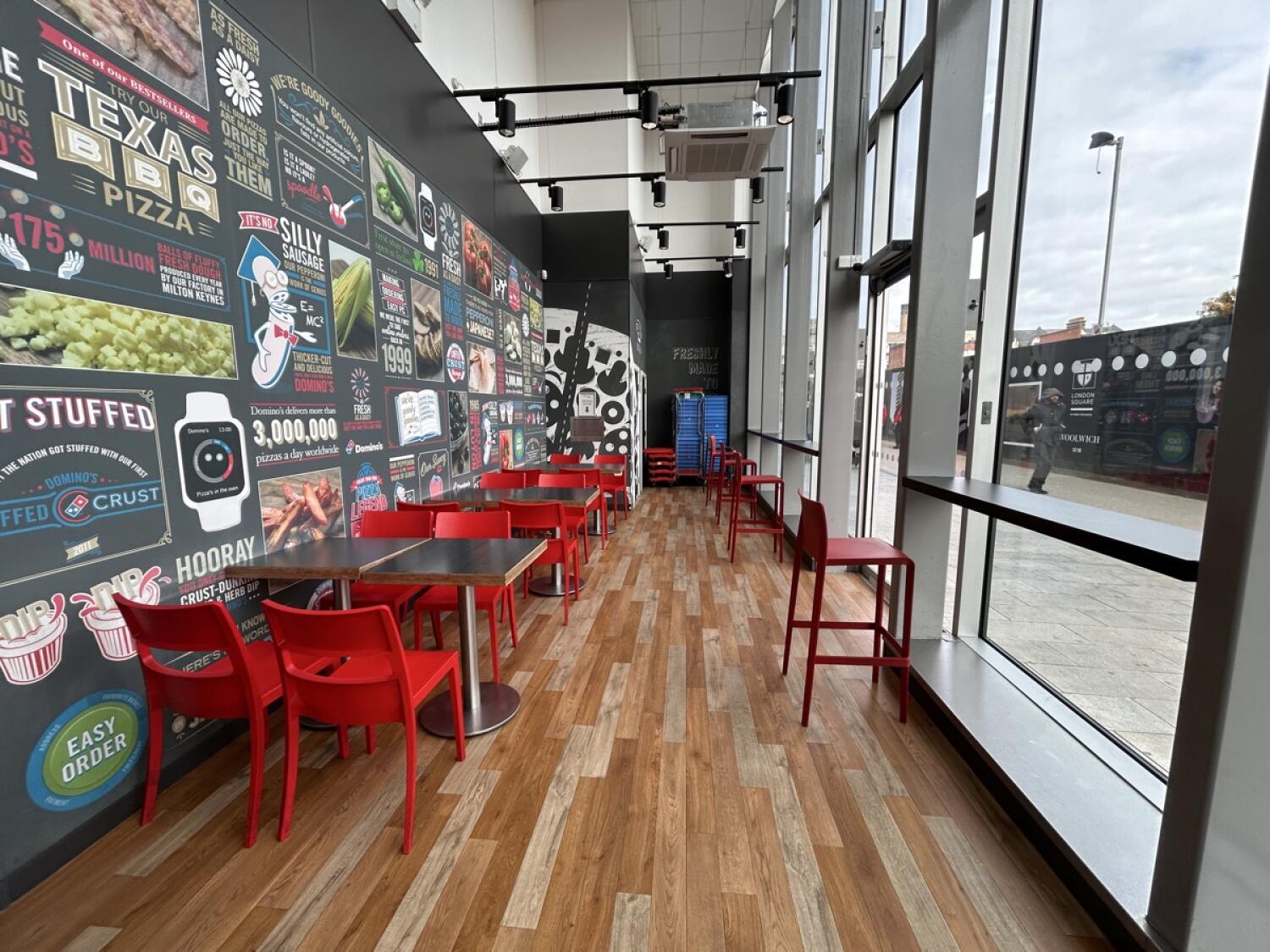 From end of ramp facing straight. Chairs and tables along left wall. Toilet behind. Stools and high-tables along right wall.