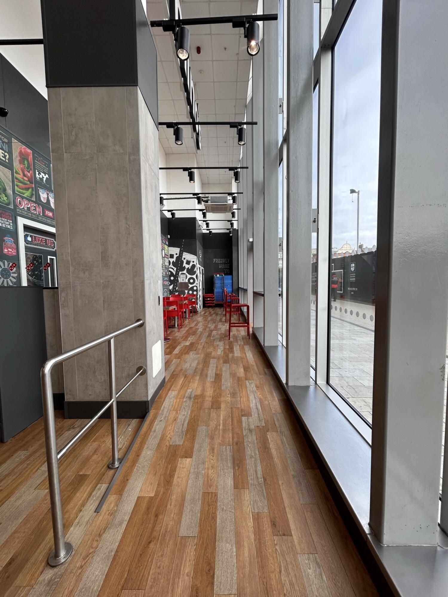 From entrance facing right. Ramp going up towards more seats. Grey metal hand-rail on left. Seats behind.