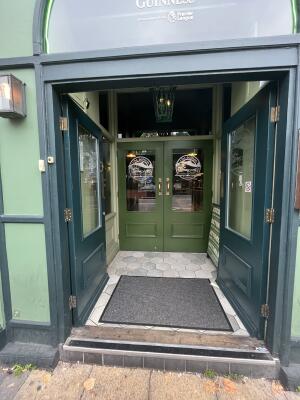 Glass double door with green wooden frame. Metal plates at centre. Push to open.