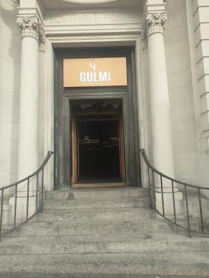 From sidewalk facing venue. Stairs to venue archway ahead. Grey handrails on both sides.