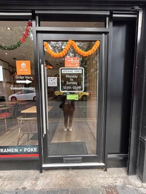 Glass door with black metal frames ahead. Push metal bar on left to open.