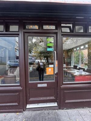 From sidewalk facing venue. Brown framed half glass door ahead. Push silver handle on right to open.